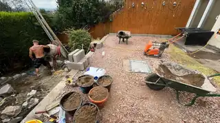 A garden mid-build, with mixers and barrows of mortar around a part-laid patio