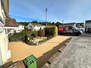 A golden resin driveway across the frontage of a bungalow, with a car parked at the far end