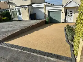 A golden resin driveway with a dark block paved border, laid up to a garage door