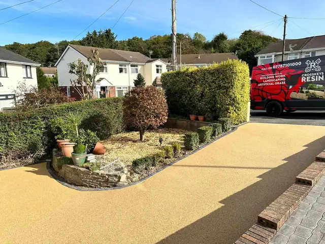 A golden resin path curving along a hedge towards the road