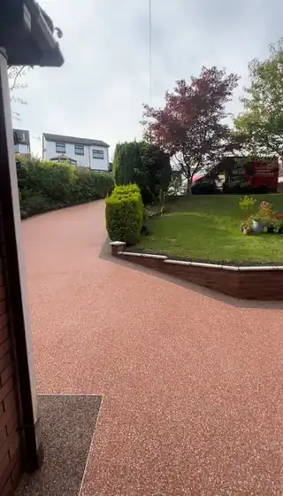 A terracotta resin path running past mature shrubs towards the front of a house