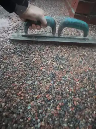 A trowel spreading terracotta resin bound stone flat