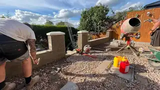 An installer laying blockwork for a low wall, with the ground dug out and levelled behind him