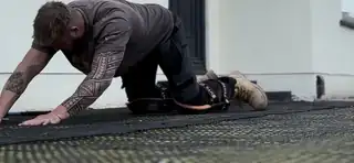 An installer working a grey epoxy floor coating out to the wall inside a garage