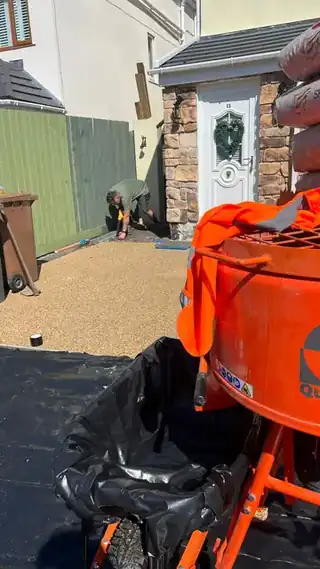 Resin and aggregate turning in a forced action mixer on site, with the batch ready alongside