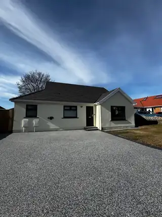 The same white bungalow from the road, its grey resin driveway sweeping to the door